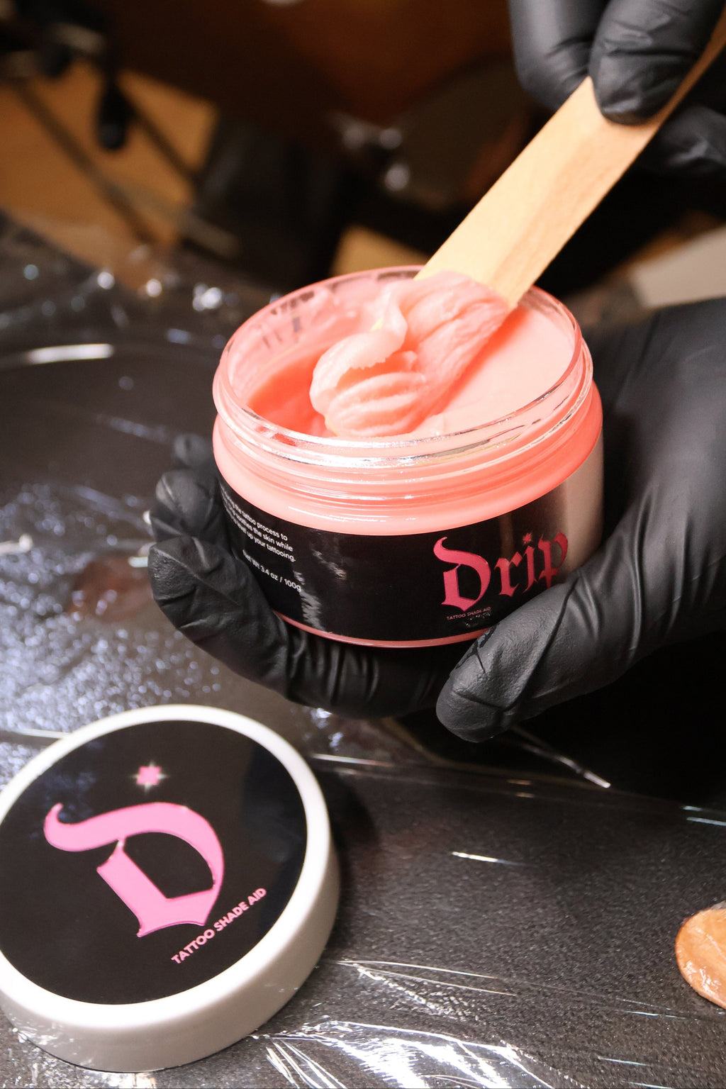 Person applying pink wax from a container labeled 'Dr' with a wooden spatula.