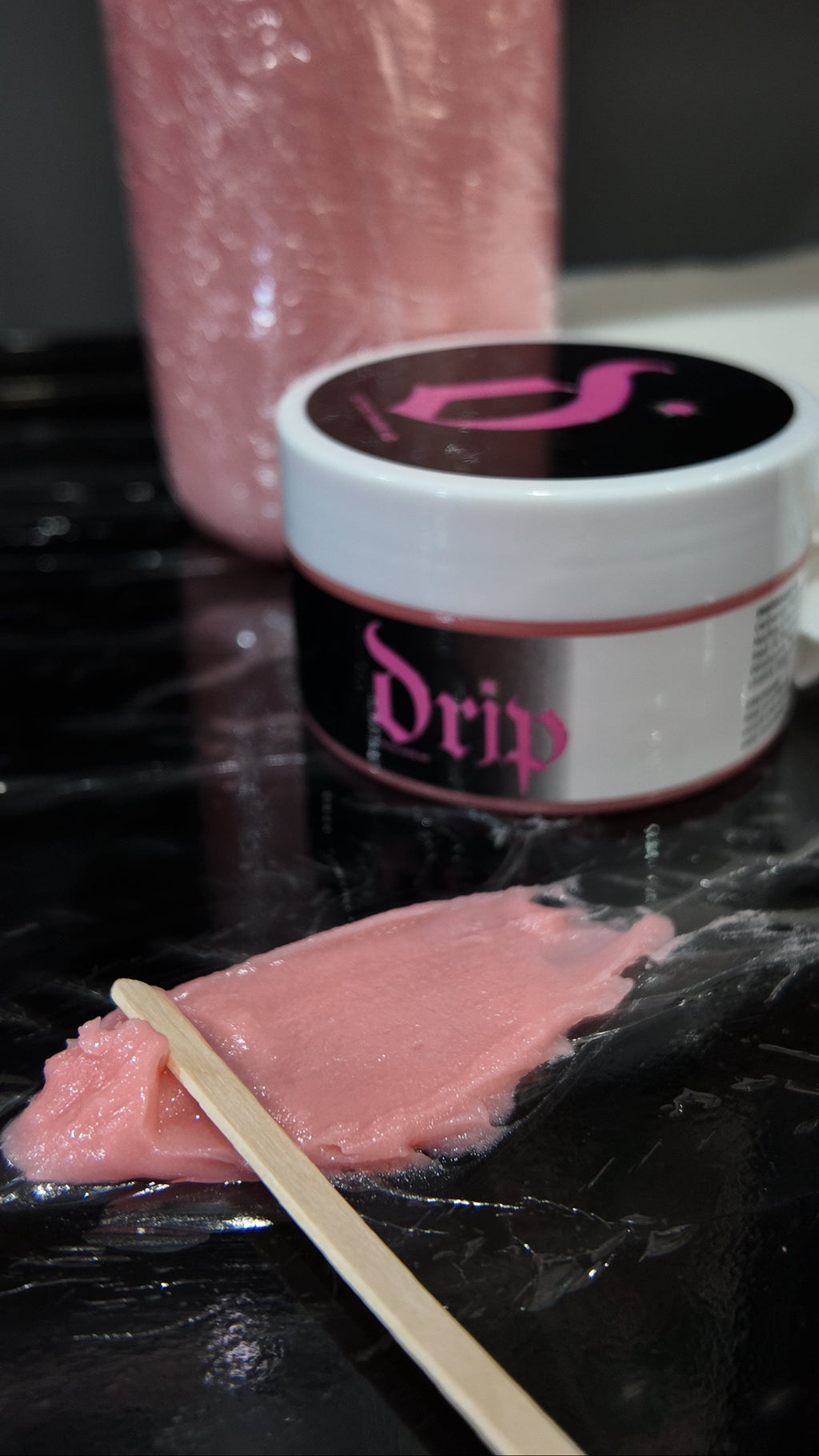 Pink substance on a stick with a container labeled 'Drip' in the background.