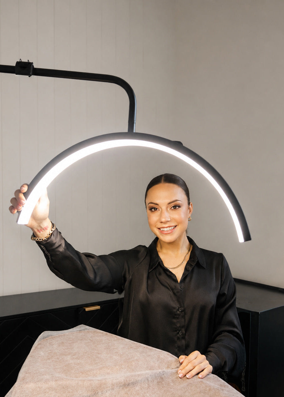 Woman holding a modern LED light fixture against a neutral background