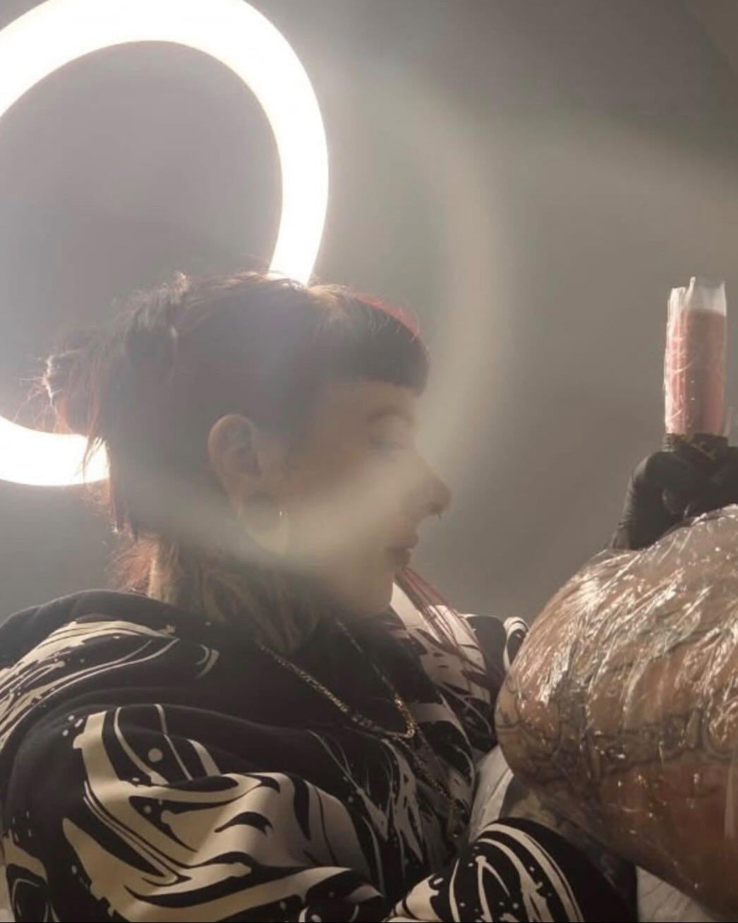 Person getting tattoo with a round light in the background